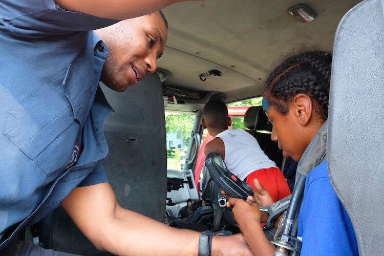 Firefighter Daryl Jones shows Jamire Thomas, 8 the smoke mask inside the firetruck at the Civc Park Art Parade.