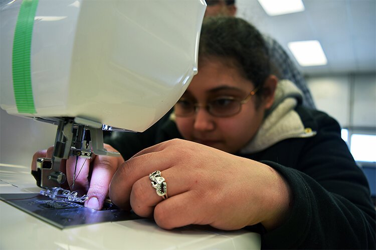 Keli Simpson, one of the makerspace’s “first adopters,” uses her skills with the sewing machine to embroider her friend’s name into a backpack strap.