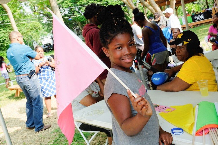 Lamariona Sims, 8 waves her flag in the wind just before her march in the Civic Park Art Parade, Thursday, July 25.