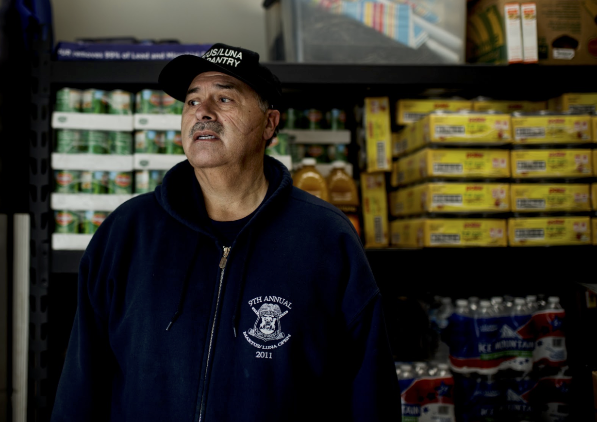 Art Luna watches Flint residents vehicles line up the Martus Luna pantry on a food distribution day.