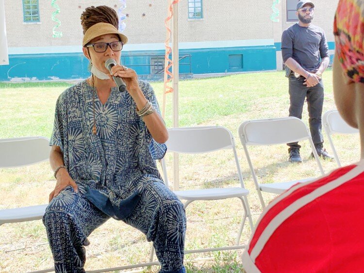 Mama Sol performing her piece "Hard to Swallow" under a tent at the Flint Town "Back to School" Carnival Splash.