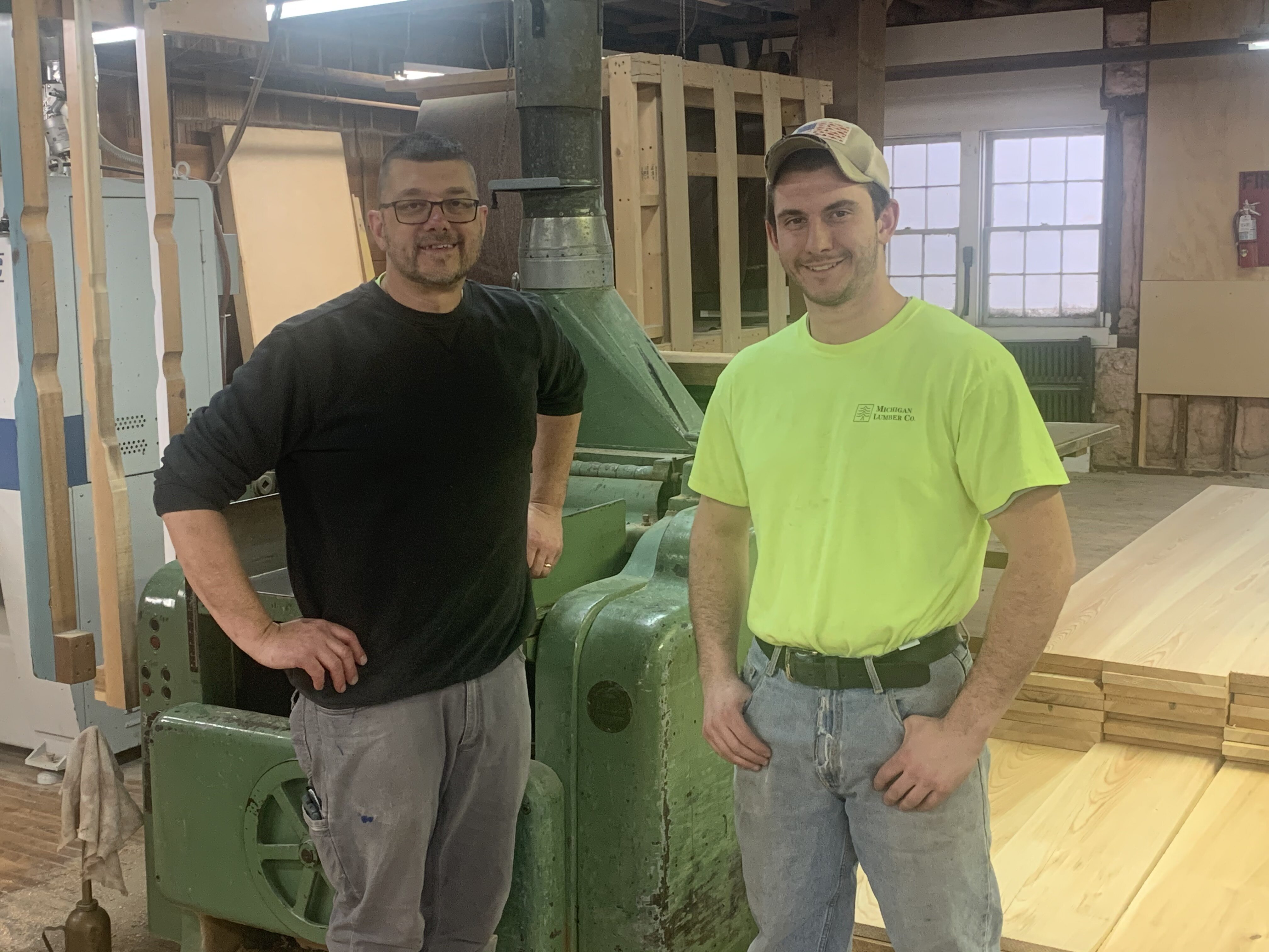 Harvey and Chris, one of several father-son duos working at Michigan Lumber, standing in front of a 60+ year old workhorse planer.