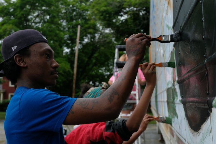 Volunteers paint the side of the water distribution trailer at Joy Tabernacle Church.