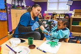 Teacher helping child at NEST Child Care and Parent Institute in Detroit.
