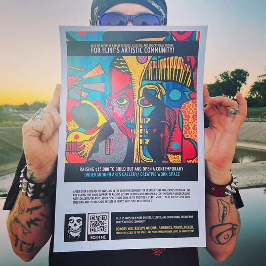Flint artist Pauly Everett holds up a poster of the current GoFundMe campaign for a new creative artspace.