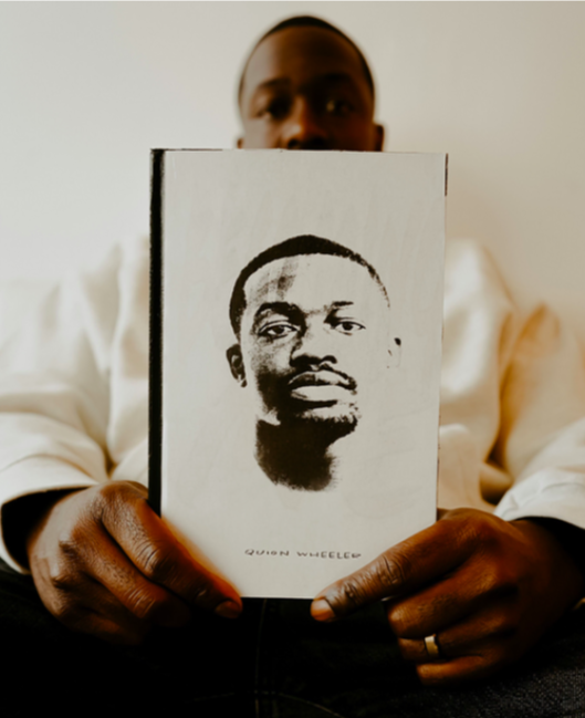 Flint native Quion Wheeler holds a copy of his debut book 'Becoming Me.'