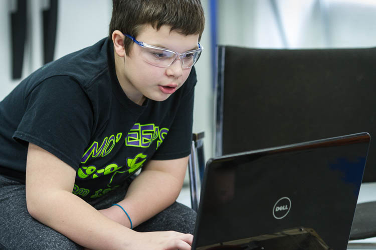 Parker Oosterhof, 12, works to program a robot for competition. He is a member of the Carman-Ainsworth Middle School team traveling to Louisville, Kentucky, for the world robotics championship competition. 