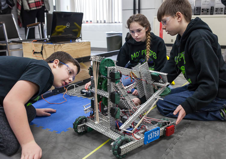 Parker Oosterhof, 12, (left); Lydia Minzey, 12; and Alex Wickham, 13, (right) work to program a robot for competition. The students are members of the Carman-Ainsworth Middle School robotics team traveling to Louisville, Kentucky for the world roboti