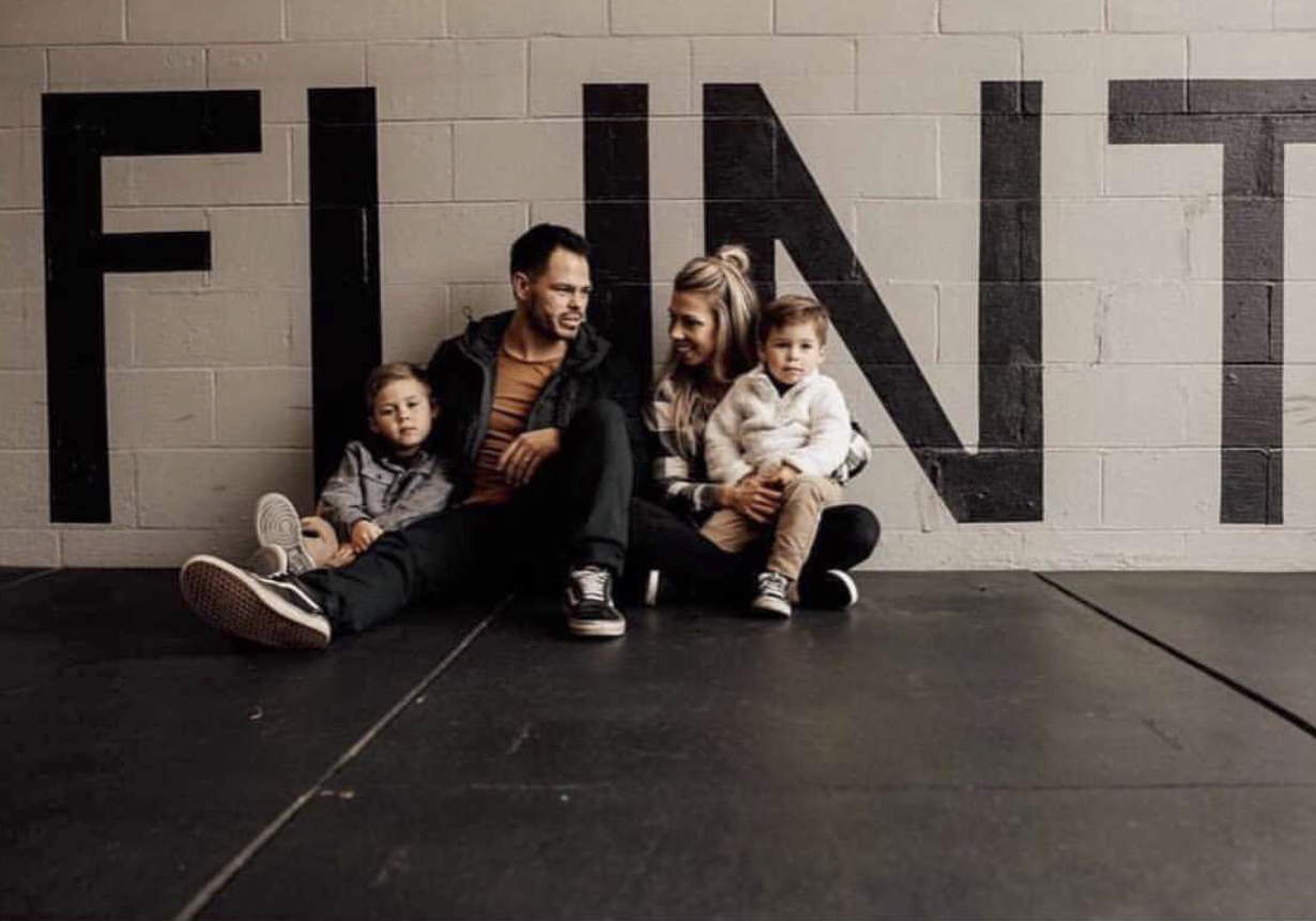 Jake and Ashleigh sit with both of their children inside Sal's Gym.