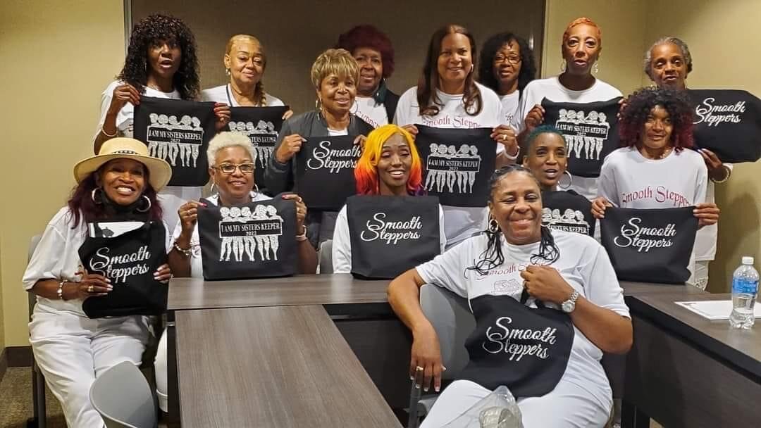The ladies of the line dancing group Smooth Steppers pose proudly with their 'Smooth Steppers' totes and “I Am My Sister’s Keeper” tees.
