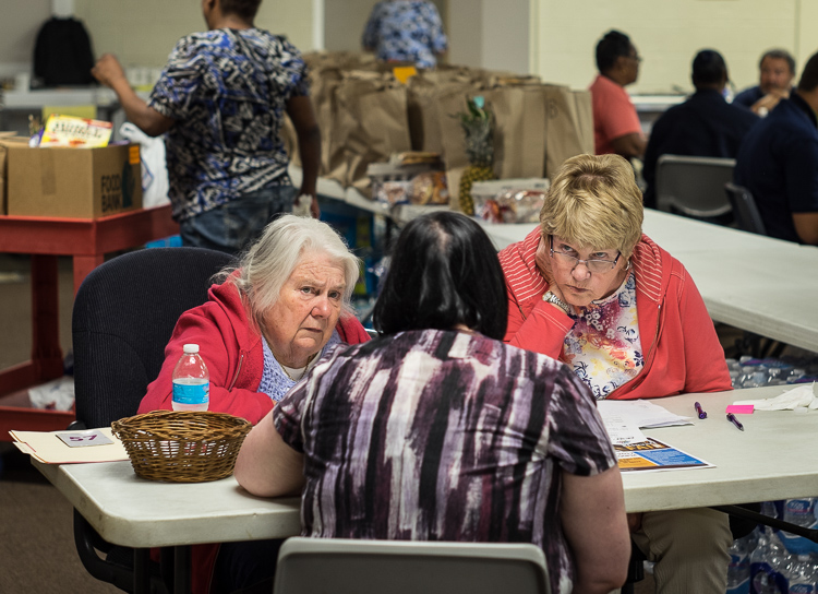 Volunteers Gaytra Molinari of Millington (left) and Elizabeth Alunno of Flushing Township (right) talk with program manager Julie Chuchvara at St. Luke's intake screening station. Here, patrons are approved to receive food.