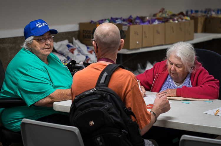 Co-founder Sister Judy Blake (left) speaks with a patron at the intake screening station at St. Luke's on Tuesday. At right is volunteer Gaytra Molinari of Millington.