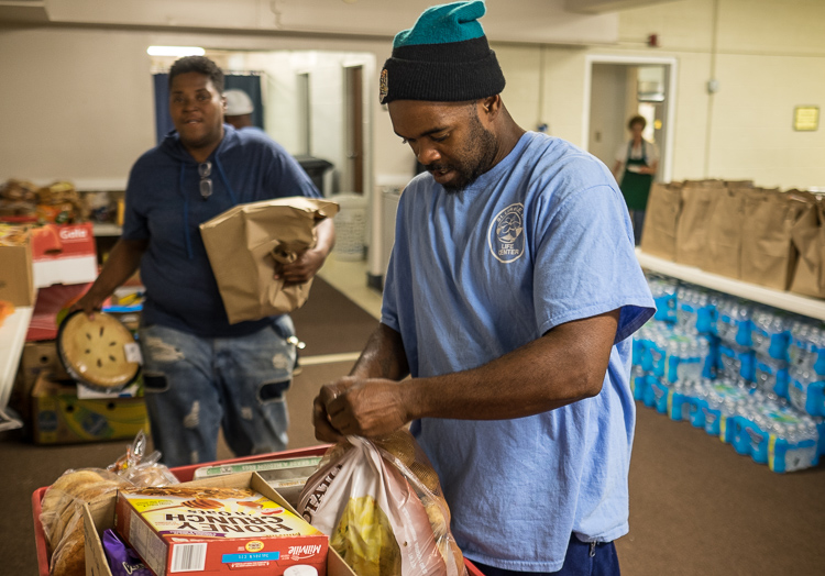 Antonio McNeal, food pantry supervisor at St. Luke N.E.W. Life Center assembles a food box that will be given to a family.