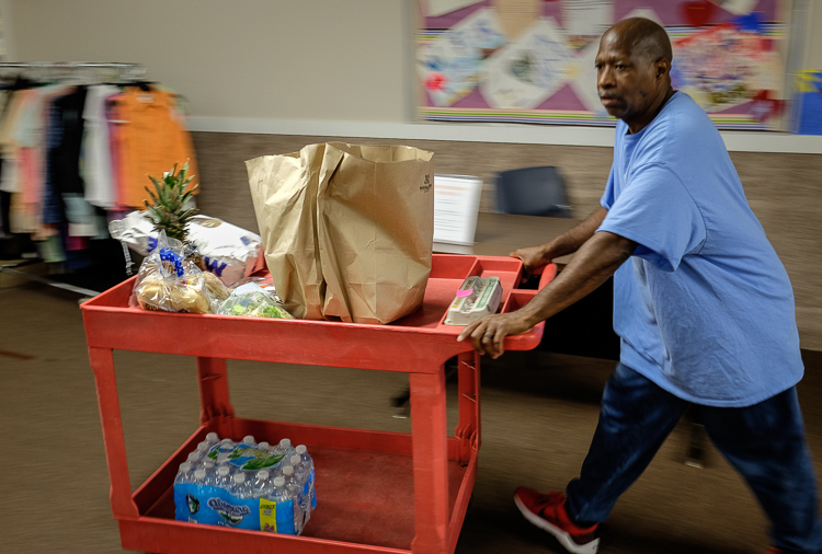 Employee Terry Taylor wheels a food donation toward a patron's car at St. Luke N.E.W. Life Center. St. Luke's receives food donations but gets food from the Food Bank of Eastern Michigan.