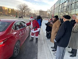 Santa and volunteers hand out gifts to FCS principals in front of the Flint Institute of Arts.