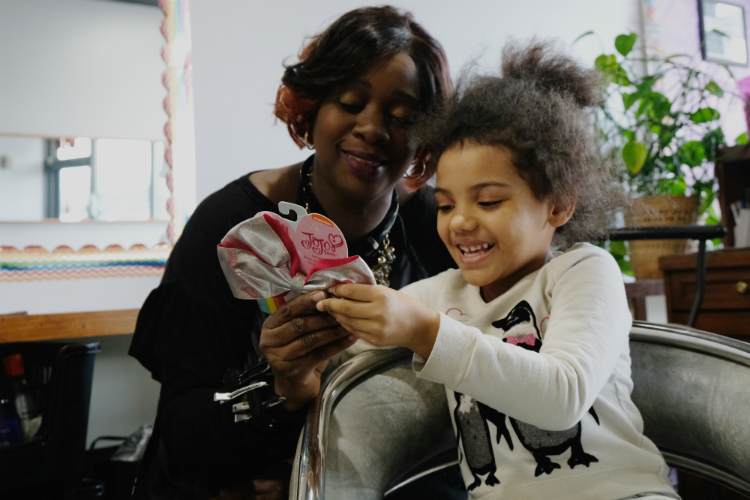 Theresa Trice-Nelson deliberates with 5-year-old Alyssa client about the placement of her Jojo Siwa bow. 