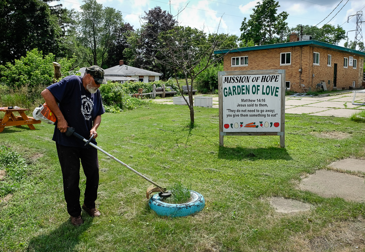 Pastor Bobby Jackson grooms the lawn at Mission of Hope Church on Roberts Street in Flint.