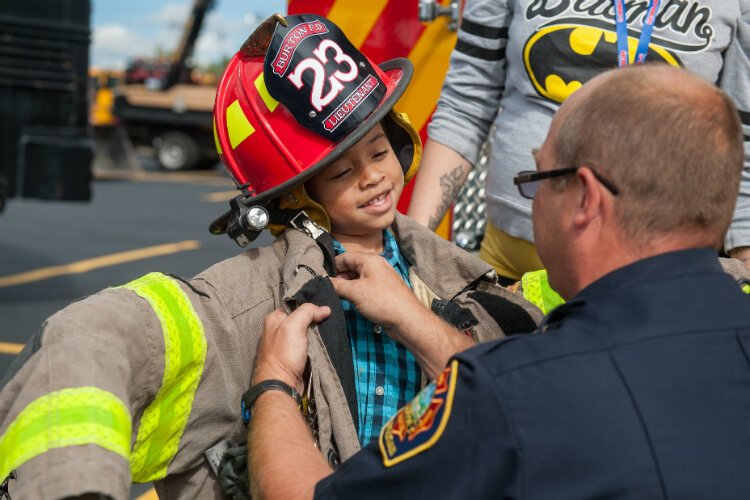 A child tries on firefighter equipment during a previous UM-Flint Touch-a-Truck. 