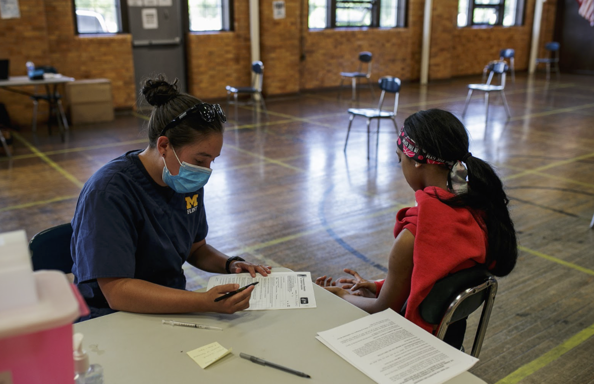 Gabby Garcia, a UM-Flint nursing student, prepares to administer the COVID-19 vaccine to Alana Thomas.