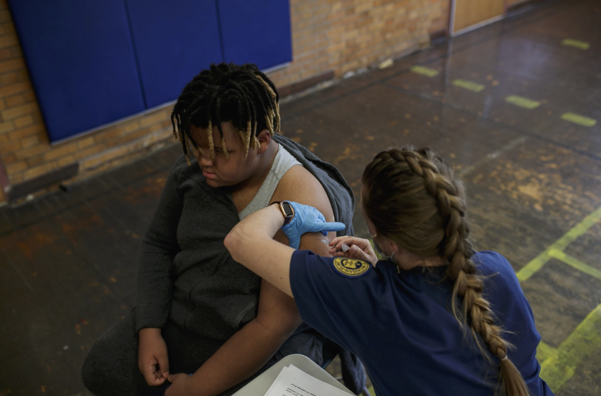 Troy Huddleston, 12, receives his second COVID-19 vaccine from Gabi Mundt, a Uof M Flint nursing student, at the Berston Field House Vaccine Clinic.