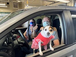 A couple gives a thumbs up from their vehicle at a previous Genesee Health Plan drive-thru vaccine event as their cute pet looks on. 