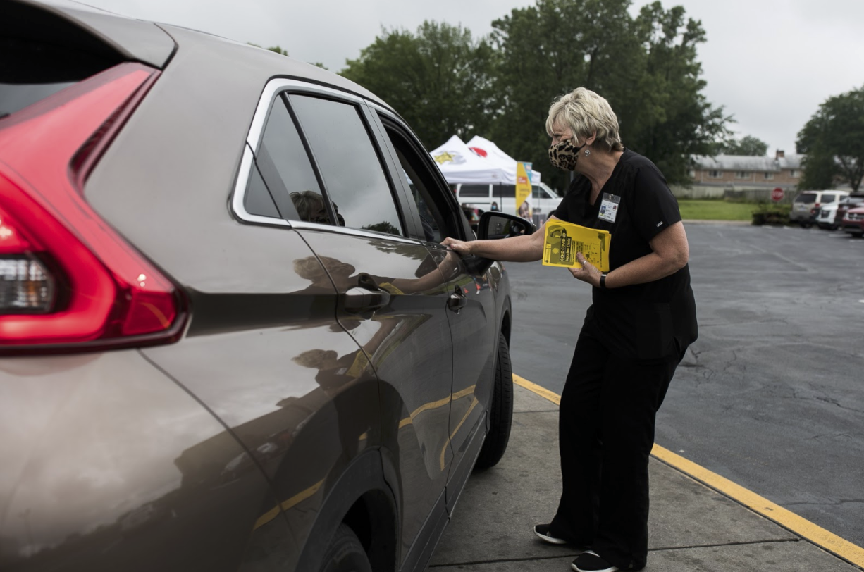 A GCHD nurse hands out flyers to cars in the McDonald's drive through for the mobile COVID-19 vaccine clinic on Miller Road.
