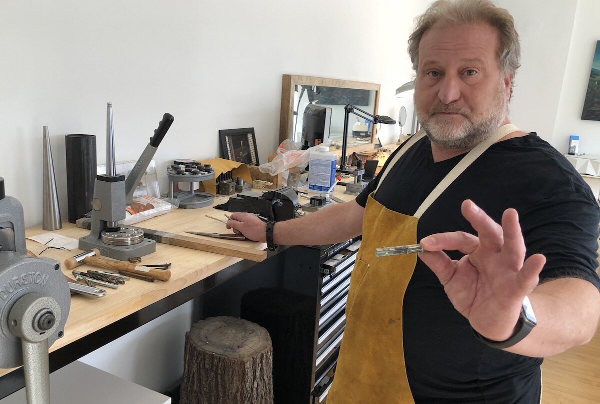 Walter McAdow holds up a piece of metal that will be crafted into jewelry.