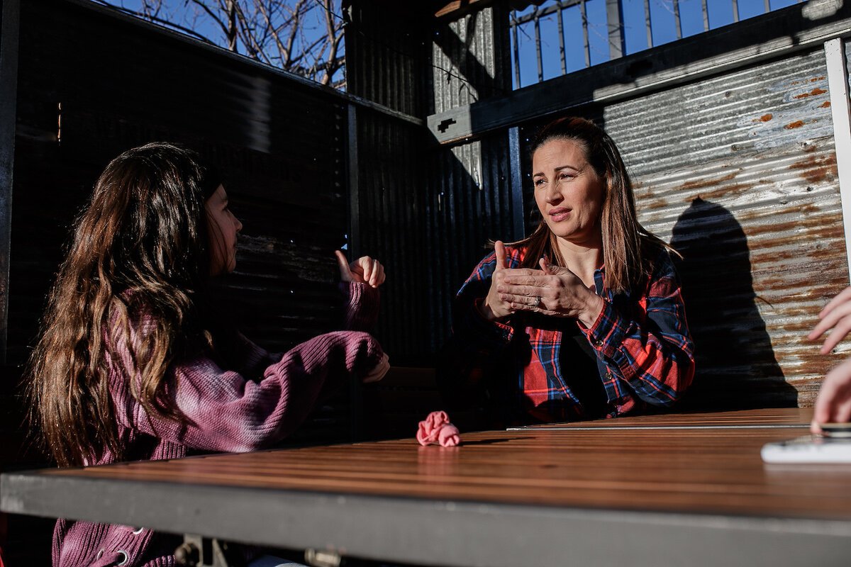 Yuliette and Giselle Parks sign to one another while sitting outside.